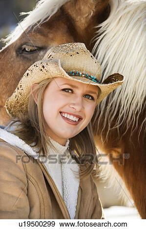 Young woman wearing cowboy hat and smiling at viewer next to horse View Large Photo Image Stock Photo - Young woman wearing cowboy hat and smiling at viewer next to horse. Fotosearch