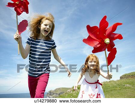 2 girls laughing with red windmills View Large Photo Image Stock Image - 2 girls laughing with red windmills. Fotosearch