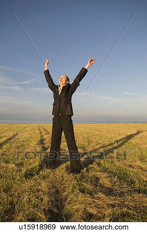 Business woman in a field with arms up View Large Photo Image Stock Photo - Business woman in a field with arms up. Fotosearch