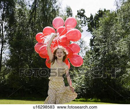 Stock Image - Girl holding bunch of red balloons. Fotosearch