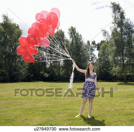 Stock Image - Girl holding bunch of red balloons. Fotosearch