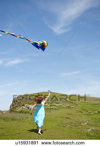 Stock Image - Girl running with kites in field. Fotosearch