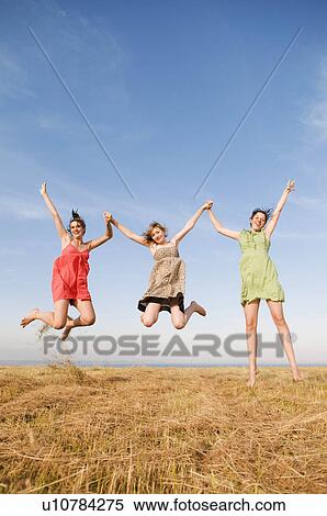Three girls jump and hold hands up high View Large Photo Image Stock Photography - Three girls jump and hold hands up high. Fotosearch