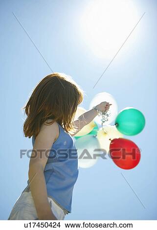 Young girl holding balloons into sky View Large Photo Image Picture - Young girl holding balloons into sky. Fotosearch
