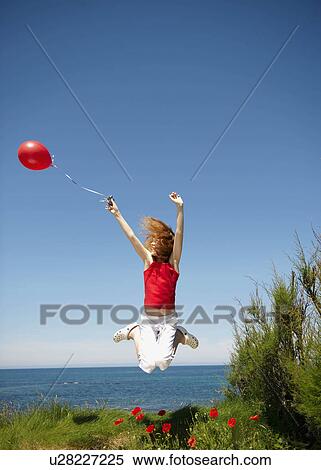 Young girl jumping with red balloon View Large Photo Image Stock Photography - Young girl jumping with red balloon. Fotosearch