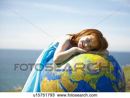 Stock Image - Young girl lying on inflatable globe. Fotosearch