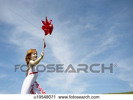 Stock Image - Young girl running with windmill. Fotosearch