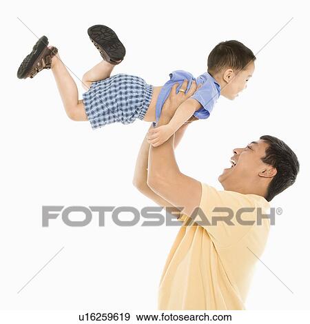 Stock Photo - Asian father lifting son up into air in front of white background.. Fotosearch