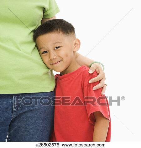Stock Photograph - Asian mother standing with arm around son.. Fotosearch