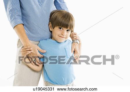 Stock Image - Boy standing with mother against white background.. Fotosearch