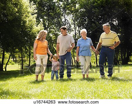 Family holding hands walking across grass in park smiling View Large Photo Image Stock Image - Family holding hands walking across grass in park smiling. Fotosearch