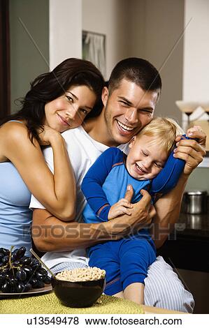 Stock Photo - Family with toddler son in kitchen at breakfast smiling. Fotosearch