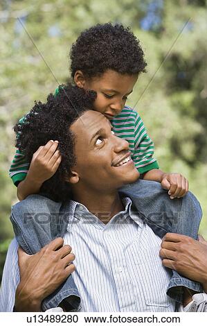Father carrying son on shoulders in park View Large Photo Image Stock Image - Father carrying son on shoulders in park. Fotosearch