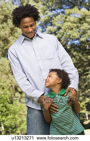 Father with hands on son's shoulders as boy looks up at him View Large Photo Image Stock Image - Father with hands on son's shoulders as boy looks up at him. Fotosearch
