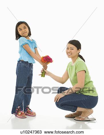 Stock Image - Girl giving her mother a bouquet of flowers.. Fotosearch