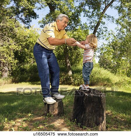 Grandfather and granddaughter playing outside holding hands balancing on stumps View Large Photo Image Stock Photography - Grandfather and granddaughter playing outside holding hands balancing on stumps. Fotosearch