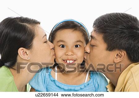 Mother and father kissing opposite cheeks of smiling daughter View Large Photo Image Picture - Mother and father kissing opposite cheeks of smiling daughter. Fotosearch