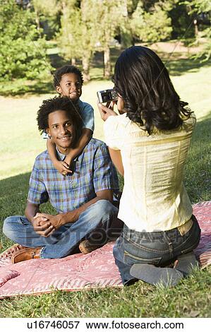 Mother photographing son and husband with digital camera in park. View Large Photo Image Stock Photo - Mother photographing son and husband with digital camera in park.. Fotosearch