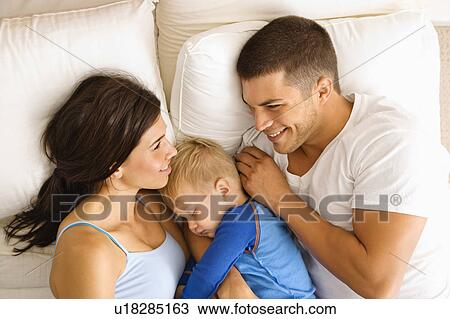 Stock Image - Parents with toddler son sleeping in bed. Fotosearch
