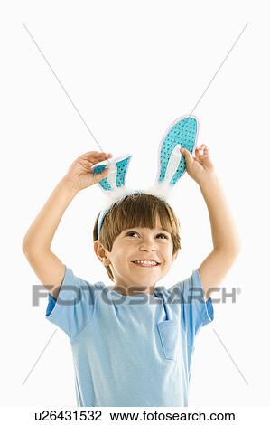 Stock Image - Portrait of boy wearing rabbit ears smiling.. Fotosearch