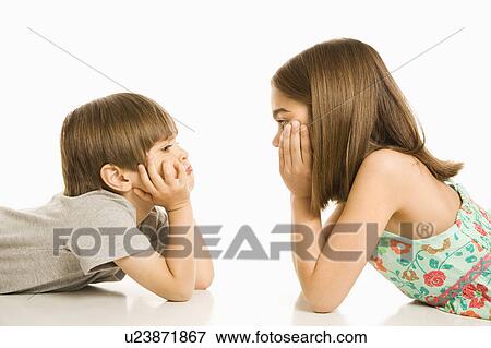 Stock Photo - Portrait of girl and boy laying down looking at each other. Fotosearch