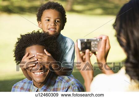 Stock Photo - Woman photographing son in park with digital camera. Fotosearch