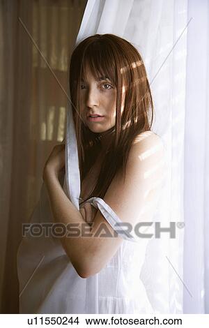 Portrait of pretty Caucasian young woman standing in sunlit curtains. View Large Photo Image Picture - Portrait of pretty Caucasian young woman standing in sunlit curtains.. Fotosearch