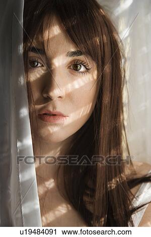 Portrait of pretty Caucasian young woman standing in sunlit curtains. View Large Photo Image Stock Image - Portrait of pretty Caucasian young woman standing in sunlit curtains.. Fotosearch