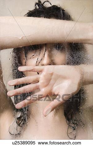 Stock Photography - Pretty Caucasian young woman wet in shower leaning against glass.. Fotosearch