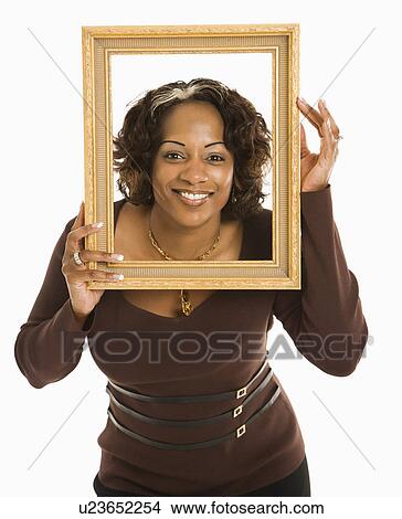 Picture - Woman holding empty frame around head smiling. Fotosearch