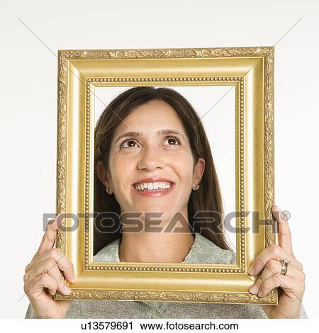 Woman holding frame in front of face smiling. View Large Photo Image Stock Image - Woman holding frame in front of face smiling.. Fotosearch