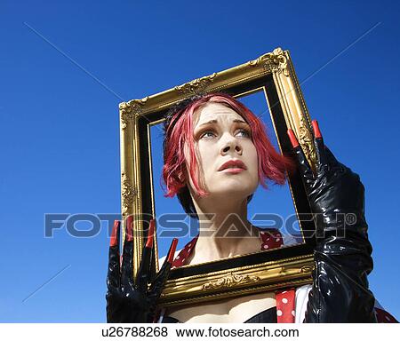 Stock Photo - Young adult Caucasian female holding empty frame around head.. Fotosearch