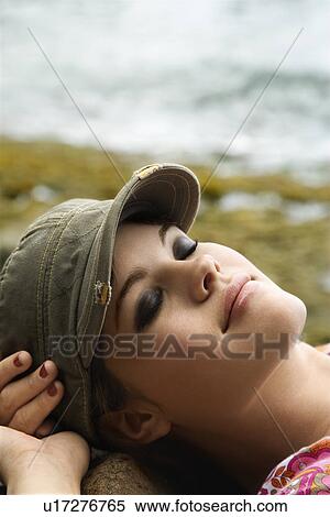 Young woman wearing hat laying down with hands behind head View Large Photo Image Stock Photography - Young woman wearing hat laying down with hands behind head. Fotosearch