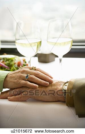 Stock Image - Couple at table holding hands. Fotosearch