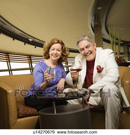 Stock Photo - Couple sitting in bar lounge having drinks and smiling. Fotosearch
