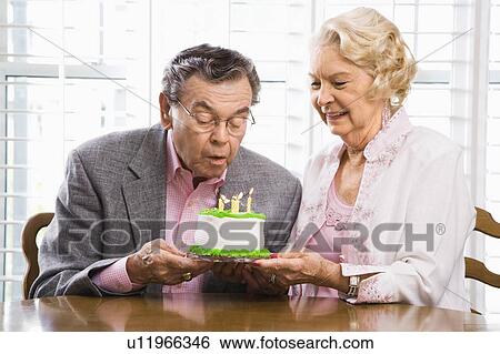 Man blowing candles out on birthday cake while woman watches View Large Photo Image Stock Photograph - Man blowing candles out on birthday cake while woman watches. Fotosearch