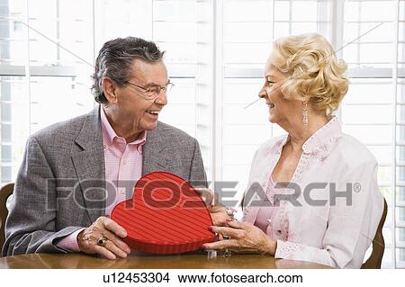 Picture - Man giving Valentine heart box to woman. Fotosearch