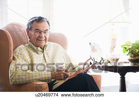 Picture - Man sitting in chair reading a book. Fotosearch