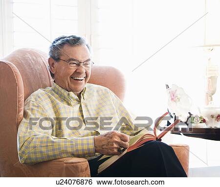 Stock Photograph - Man sitting in chair reading a book. Fotosearch