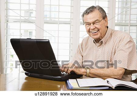 Stock Photo - Man typing on laptop in home. Fotosearch