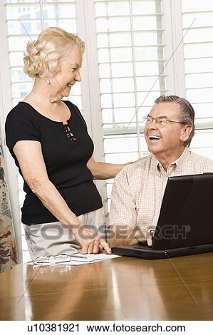 Stock Image - Mature Caucasian couple looking at laptop.. Fotosearch