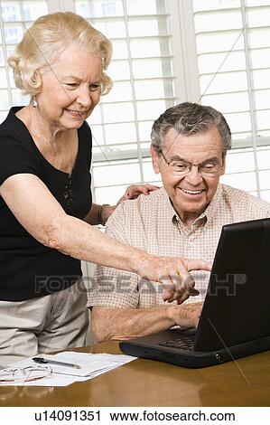 Stock Image - Mature Caucasian couple looking at laptop.. Fotosearch