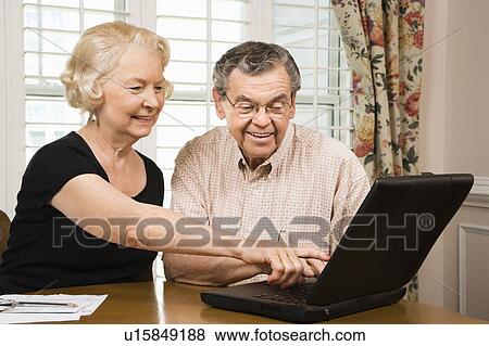 Stock Photo - Mature Caucasian couple looking at laptop.. Fotosearch