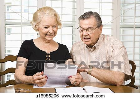 Stock Photograph - Mature Caucasian couple looking at their bills.. Fotosearch