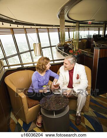 Mature Caucasian couple sitting in bar lounge having drinks and talking. View Large Photo Image Picture - Mature Caucasian couple sitting in bar lounge having drinks and talking.. Fotosearch