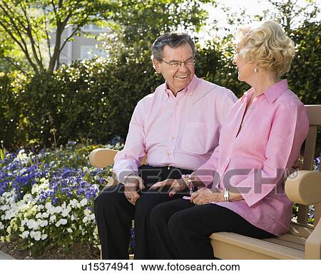 Mature Caucasian couple sitting on bench looking at each other. View Large Photo Image Stock Image - Mature Caucasian couple sitting on bench looking at each other.. Fotosearch