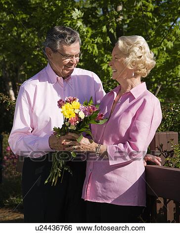 Mature Caucasian man giving mature Caucacsian woman flowers. View Large Photo Image Stock Photograph - Mature Caucasian man giving mature Caucacsian woman flowers.. Fotosearch