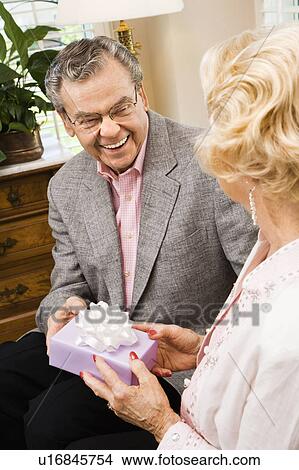Picture - Mature Caucasian man giving present to mature Caucasian woman.. Fotosearch