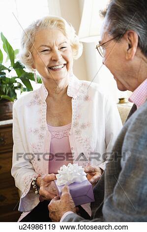 Mature Caucasian man giving present to mature Caucasian woman. View Large Photo Image Stock Photo - Mature Caucasian man giving present to mature Caucasian woman.. Fotosearch