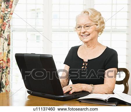 Mature Caucasian woman using laptop in living room. View Large Photo Image Stock Image - Mature Caucasian woman using laptop in living room.. Fotosearch